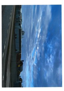 Fotografi av en bygning (eller en rekke container/containere) sett fra siden, med en skyet himmel i bakgrunnen.