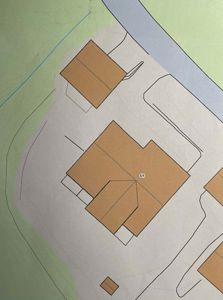 Situasjonsplan som viser tomtens form, bebyggelse (hus og garasje), veier, og omgivelsene (grøntområder/vann).