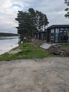 Fotografi av en byggeplass med moderne hus langs vannet under utgravning.
