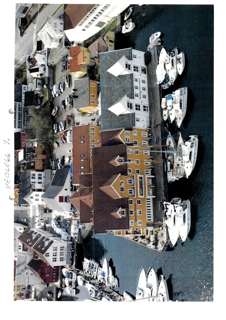 Fotografi av en havn med båter og bygninger sett fra luften.