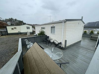 Fotografi av en hvit mobilheim med en terrasse, sett fra en høyde.