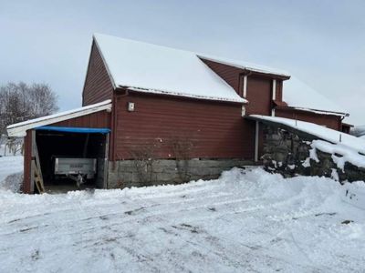 Fotografi av en rød bygning med snø på taket og i omgivelsene.