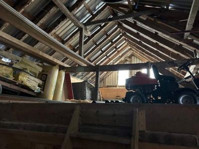 Fotografi av et loft eller etasjens takkonstruksjon med isolasjon og en traktor.