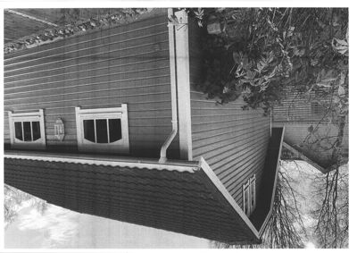 Sort-hvitt fotografi av en bygning sett fra siden, som viser fasaden, taket, vinduer og nedløp.