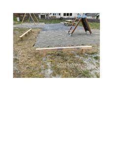 Fotografi av en utendørs rekreasjonsområde med utstyr og en bygning i bakgrunnen.