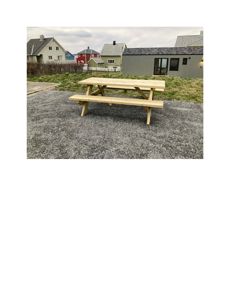 Fotografi av en utebordsbenk på en grusflate med naboegrender i bakgrunnen.