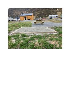 Fotografi av en byggeplass med en gul bygning i bakgrunnen og en nybetont grunnflate i forgrunnen.