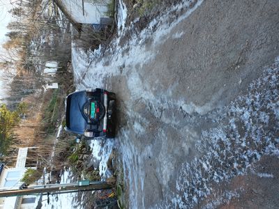 Fotografi av en bil parkert på en grusvei med snø på bakken.