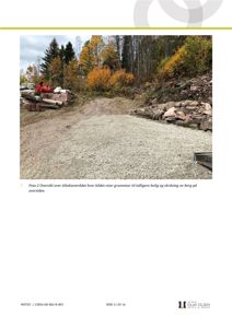 Fotografi av et utendørs område med grus, skog og en person som sitter på en loggbank.