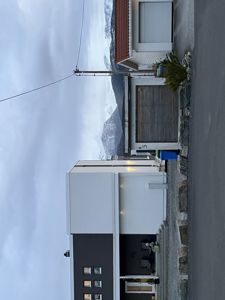 Fotografi av en moderne bolig med garasje, sett fra gaten mot en bakgrunn med fjell.