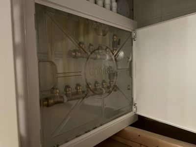 Fotografi av en installert vannfordeler (UPONOR) med gjennomsiktig deksel, sett fra innsiden av et skap.