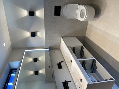 Fotografi av et moderne bad med toalett, vask og speil.