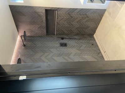 Fotografi av en dusjromsinnredning med flislagt gulv og vegger.