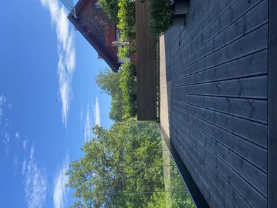 Fotografi av en utvendig terrasse med glassvegg og en nabobygning i bakgrunnen.