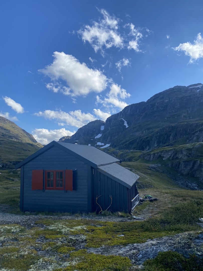 Fotografi av en liten hytte i et fjellandskap