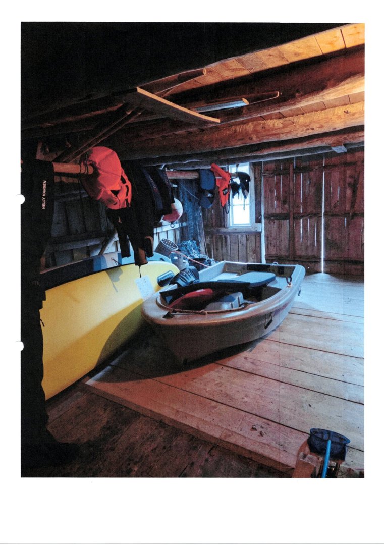 Fotografi av et innvendig rom i en bygning, sannsynligvis et båthus eller garasje, med båter og utstyr.