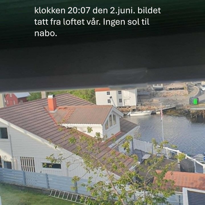 Fotografi tatt fra et loft som viser nabolaget, inkludert hus med tak, vann og en brygge.