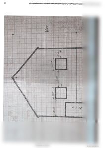 En håndskrevet tegning på millimeterpapir som viser etasjeplan for en bygning med angitte mål for rom og vegger.