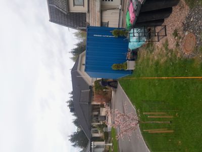 Fotografi av en bolig med en blå container i hagen.