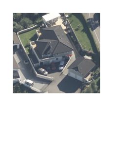 Luftfoto av en tomt med en hovedbolig, en garasje og en tilhørende bygning (kanskje uthus eller garasje).