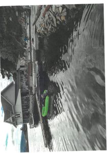 Fotografi av en bygning ved vannet med en brygge, en båt og en kai.