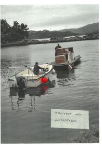 Fotografi av en båt og en flytedrygg med kasser, med en håndskrevet note om 'Transport med flytedrygge'.