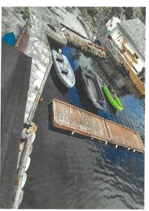 Fotografi av en kai med båter og en bygning ved vannkanten