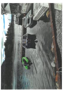 Fotografi av en kai med båter og en bygning i bakgrunnen.