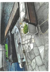 Fotografi av en kai med en båt, en brygge og en steinlagt gangvei.