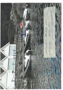 Fotografi av en brygge med båter og en hvit bygning i bakgrunnen.