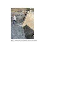 Fotografi av en betongmur som skal dekkes med naturstein, med en person som går forbi for skala.