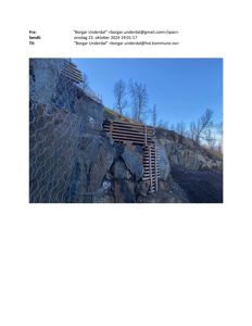 Fotografi av en steinmur med gitternett og trekonstruksjoner, sannsynligvis en del av en byggeplass eller terrengarbeid.