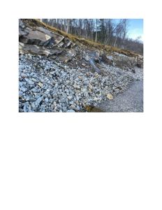 Fotografi av en steinlagt skråning eller bakke med en vei eller gangsti i forgrunnen.