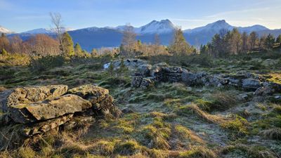 Fotografi av et landskap med fjell i bakgrunnen og steinblokker i forgrunnen.