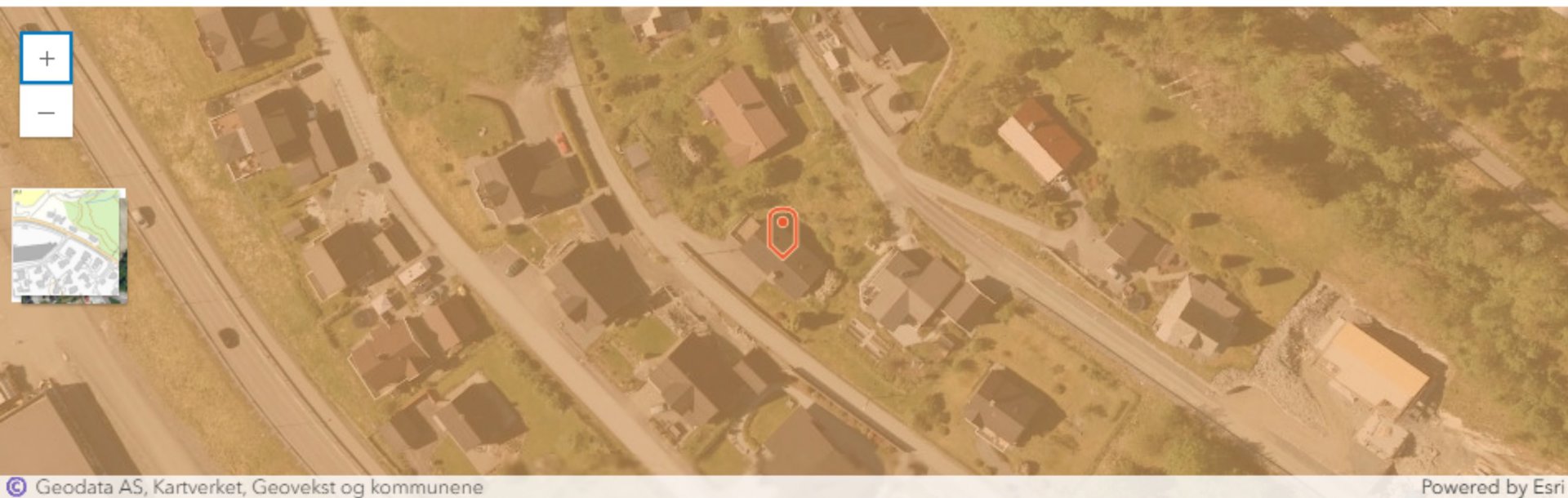 Flyfoto eller satellittbilde av et boligområde med en markert tomt (rød markør).