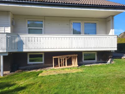 Fotografi av en bolig sett fra bakken, som viser fasaden med balkong og vinduer.