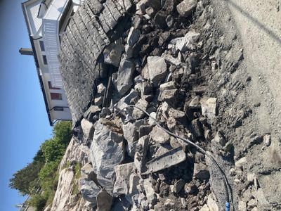 Fotografi av en steinmur eller fundament som ligger under et hus, med store blokker og grus.