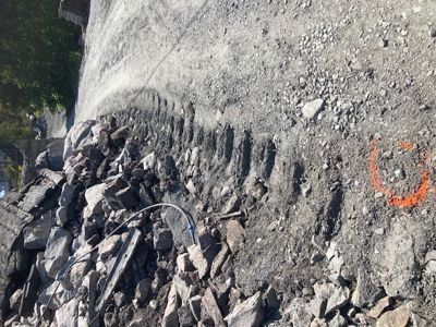 Fotografi av et byggeplassområde med steinhuggeri, grus og en orange markering på bakken.