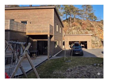 Fotografi av en ferdigbygd husfasade med tilhørende garasje og uteplass.