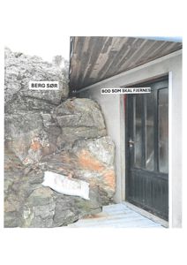 Fotografi av en utvendig vegg med en dør og en steinvegg (berg) ved siden av. Bildet har tekstmerkelapper som 'BERG SØR' og 'BOD SOM SKAL FJERNES'.