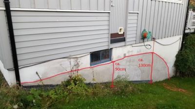 Fotografi av en bygningsside med en tegnet innmåling av fundamentets høyde.