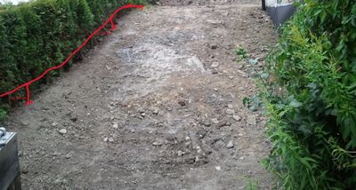 Fotografi av en grusvei eller gangvei med hegn og planter på sidene. Det er tegnet inn en rød linje og en måling på ca. 90 cm.