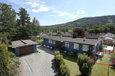 Fotografi av en blå enebolig med garasje, sett fra luft eller høy vinkel.