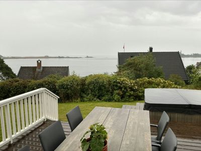 Fotografi av en terrasse med utsikt over vann og nabohus.