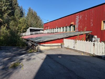 Fotografi av en rød bygning med hvit hekk og et tilhørende takverk sett fra bakkenivå.