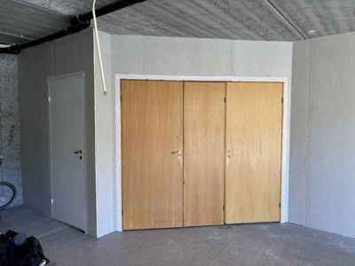 Fotografi av et uterom eller garasje med tre dører og betongvegger i en byggeprosess.