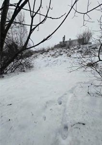 Fotografi av et snødekt landskap med en bygning i bakgrunnen.