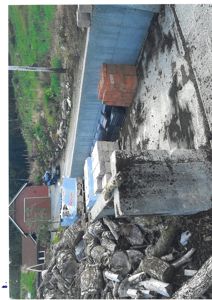 Fotografi av en byggeplass med materialer (stein, tre, murstein) og en del av en bygning i bakgrunnen.