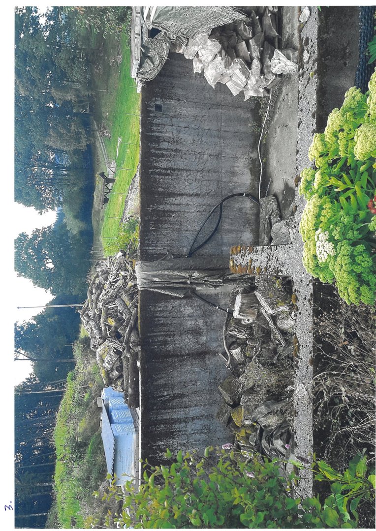 Fotografi av en utvendig vegg i en bygning, sannsynligvis en kjeller- eller underjordisk del, med tilhørende utemiljø.