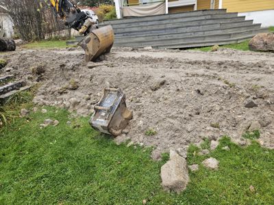 Fotografi av en byggeplass med en graver som jobber i bakken foran en eksisterende villa.